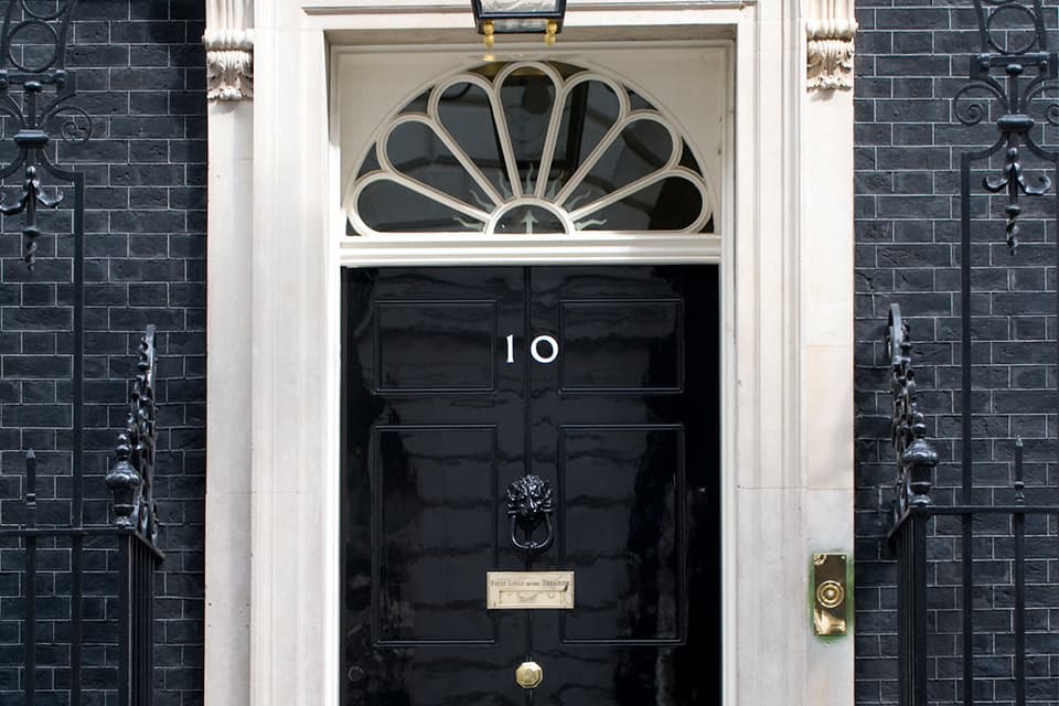 The black front door of 10 Downing Street in London, 2020. Photo: UK Government, via Wikimedia Commons (Open Government Licence v3.0). Source page: https://commons.wikimedia.org/wiki/File:10_Downing_Street_Door_2020.jpg