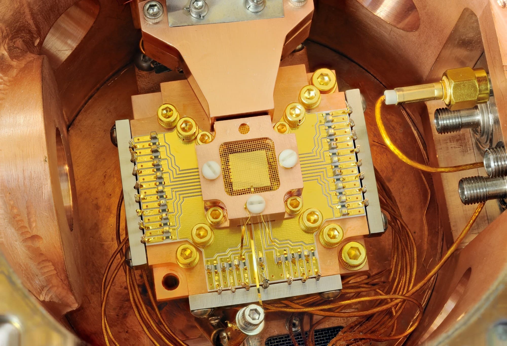 A NIST ion-trap apparatus in which two beryllium ions are held about 40 micrometers apart above a square gold chip inside a copper enclosure, 2011. Illustrative; not Quantinuum hardware. Photo: Y. Colombe/National Institute of Standards and Technology, via Wikimedia Commons (public domain). Source page: https://commons.wikimedia.org/wiki/File:Quantum_Computing;_Ion_Trapping_(5941055642).jpg