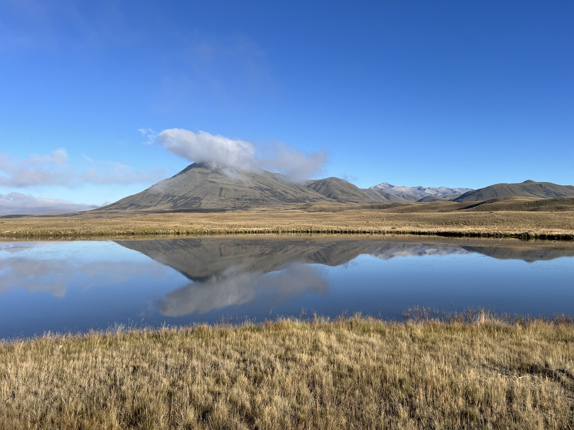 A small lake in open tussock country beneath mountains in the Ashburton Lakes district of Canterbury, New Zealand.