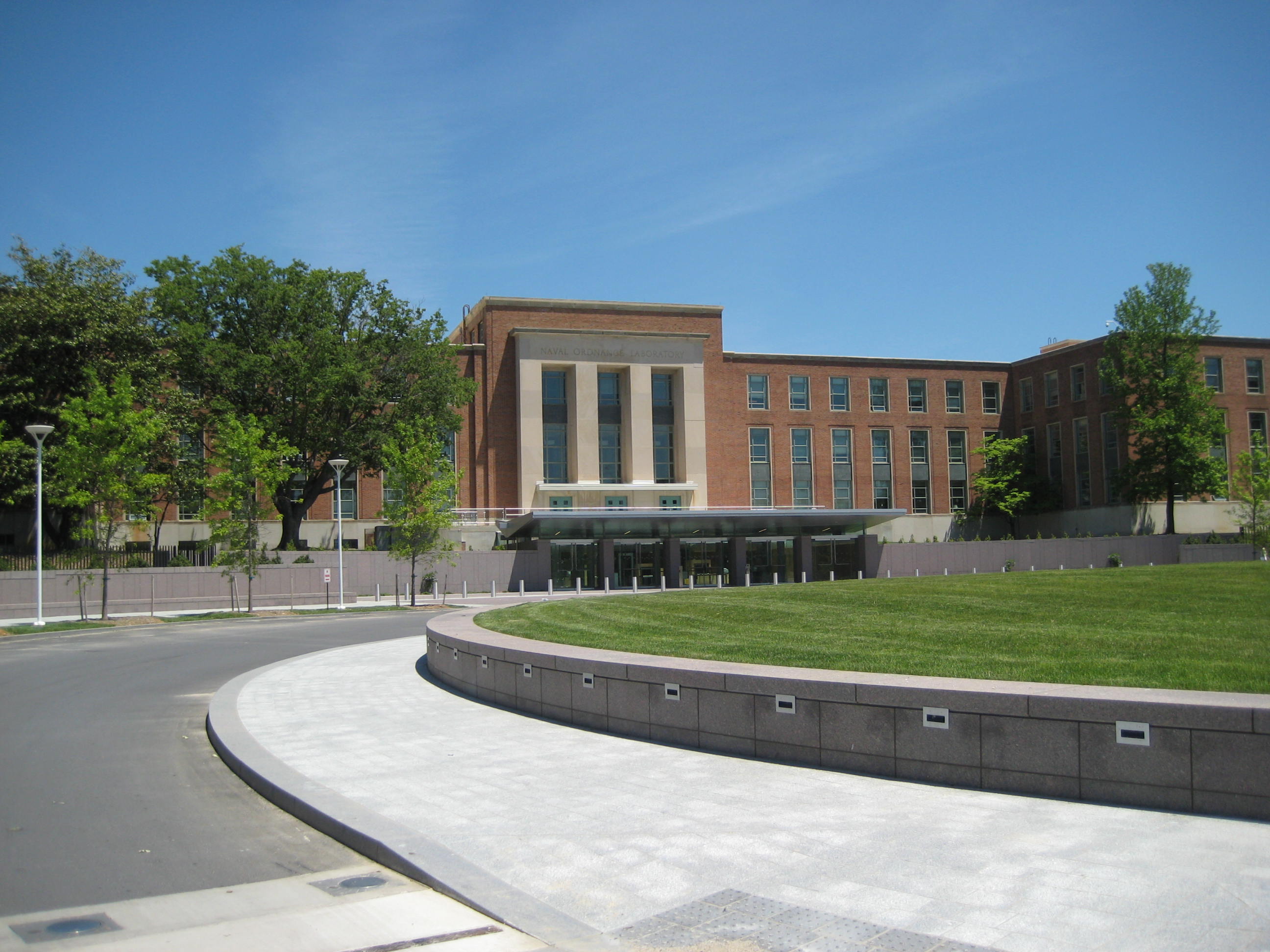A multi-story brick and glass federal office building with a circular drive and landscaped plaza at its main entrance.