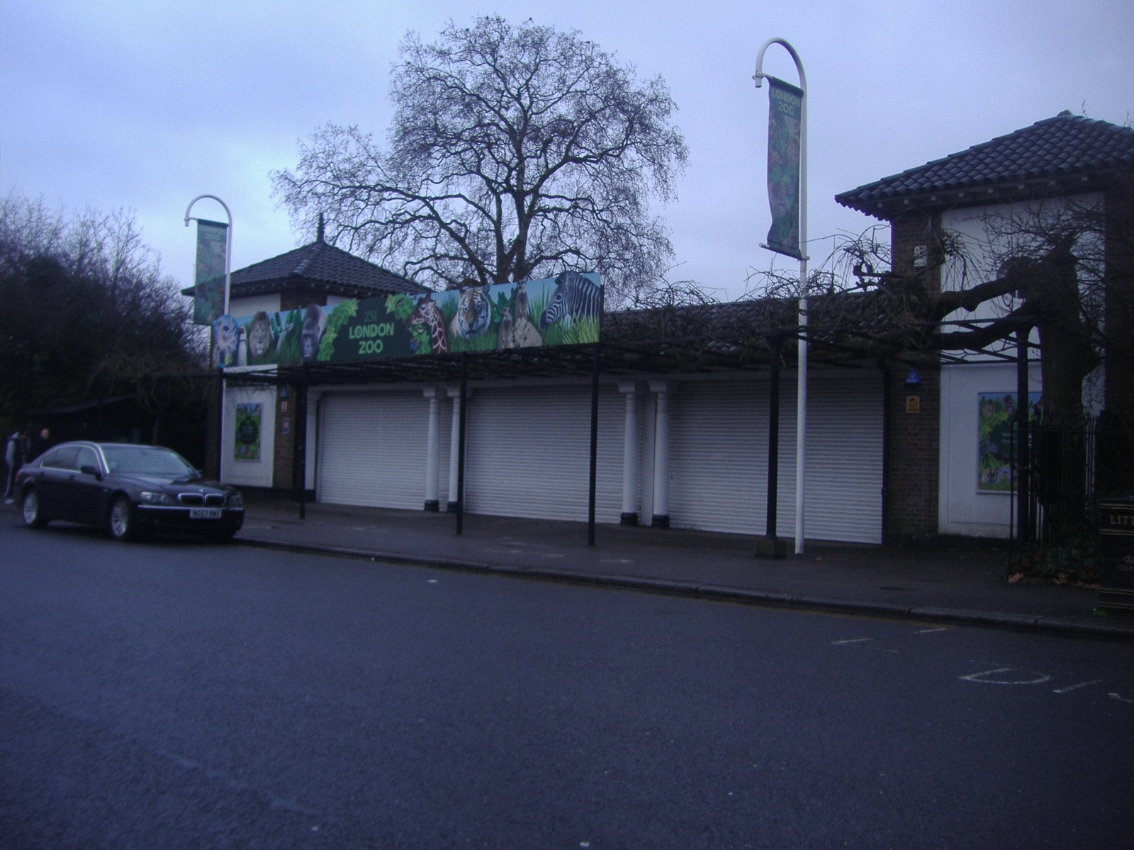 The London Zoo entrance building with its shutters closed, under a bare winter tree.