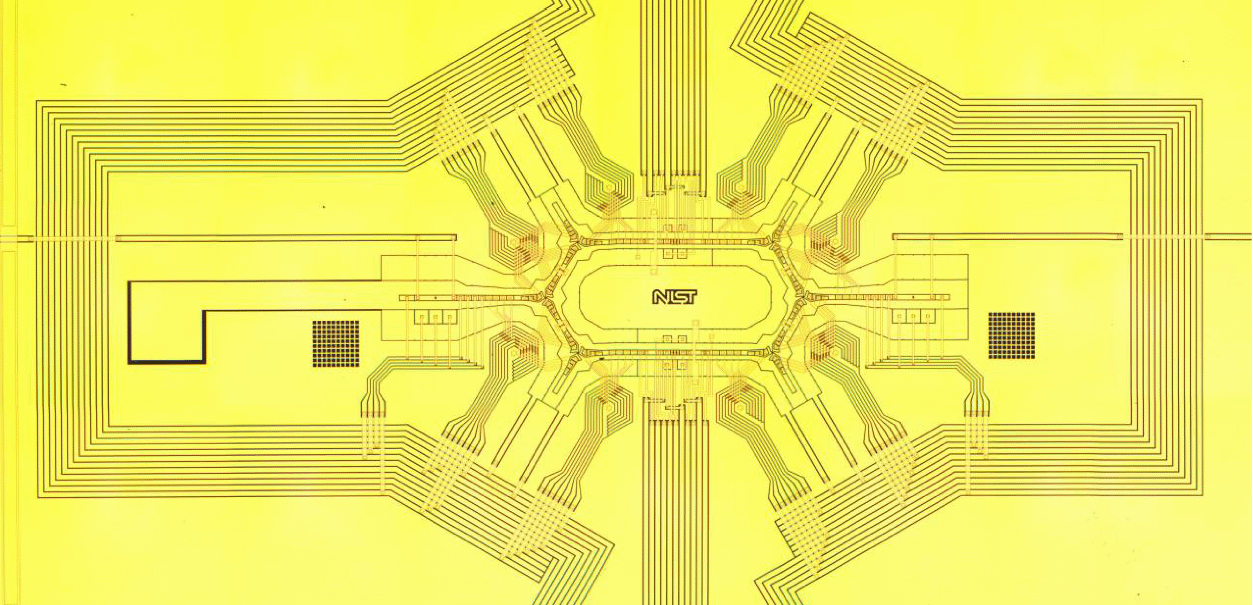 A microfabricated chip with a central ring and six channels radiating outward, used to store and move ions.