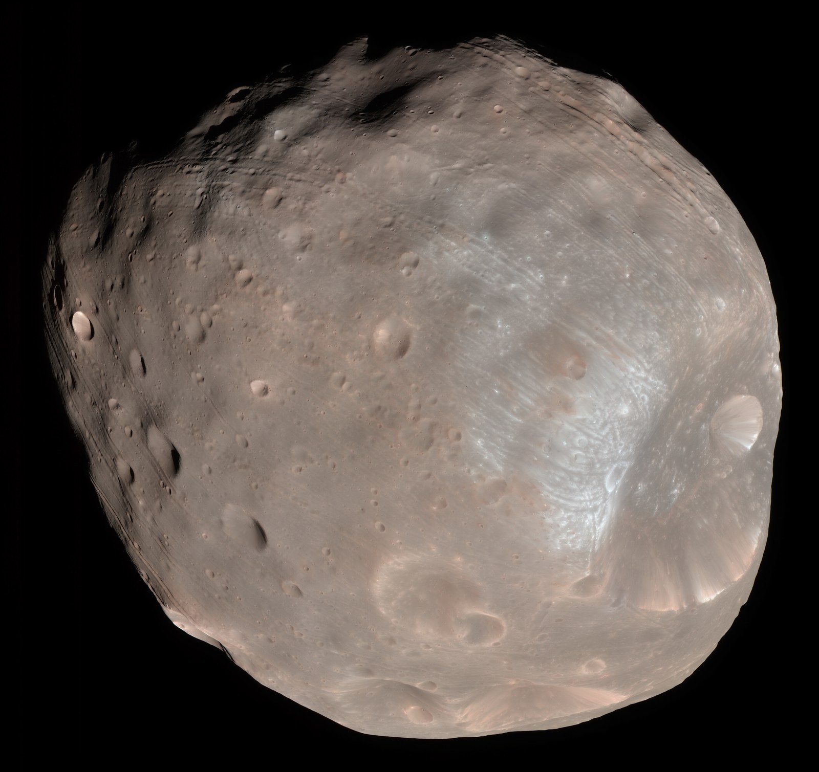 A gray, potato-shaped moon covered in craters, with a large crater at lower right, against a black background.